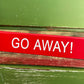 red acrylic "go away" desk sign