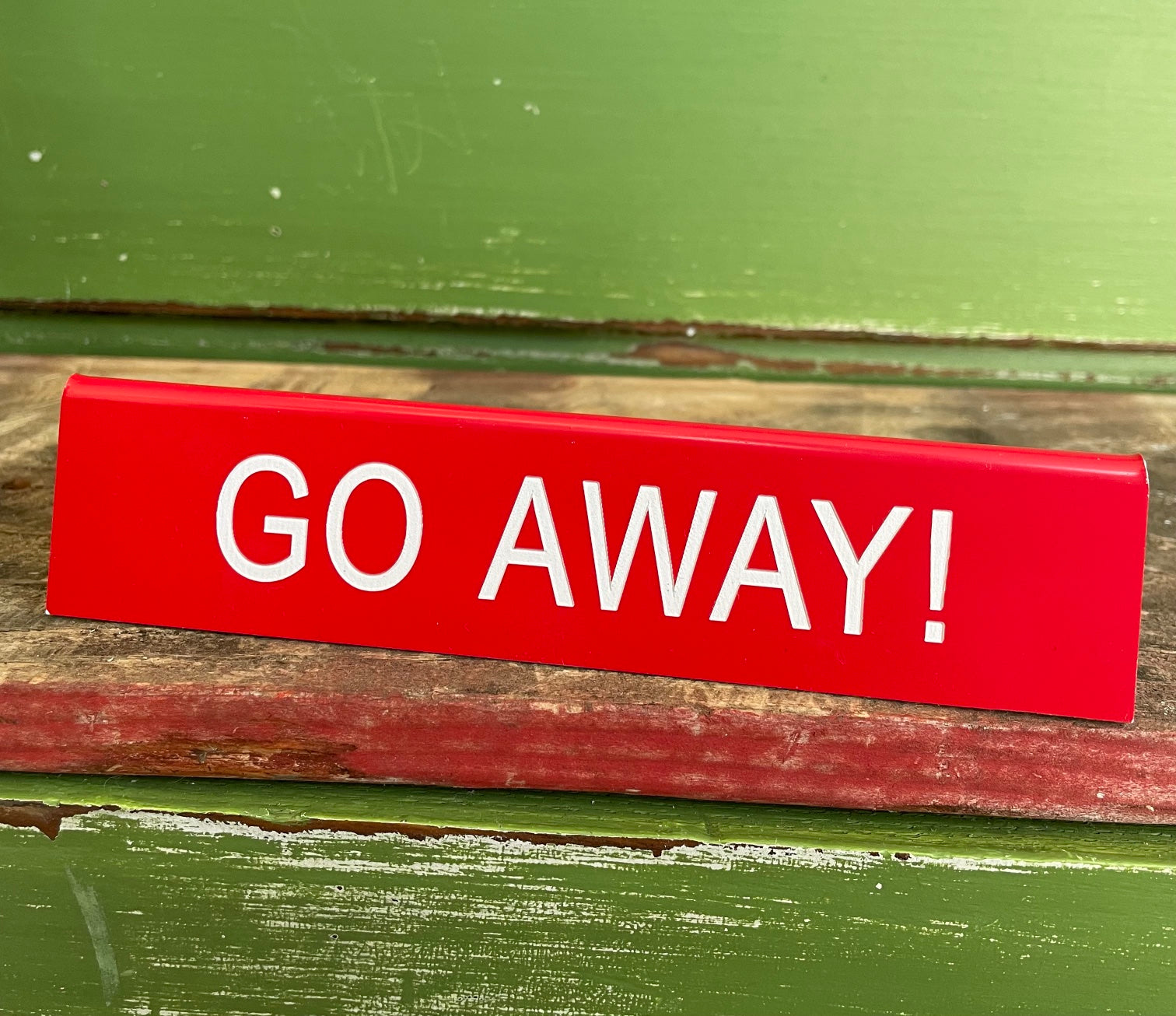 red acrylic "go away" desk sign